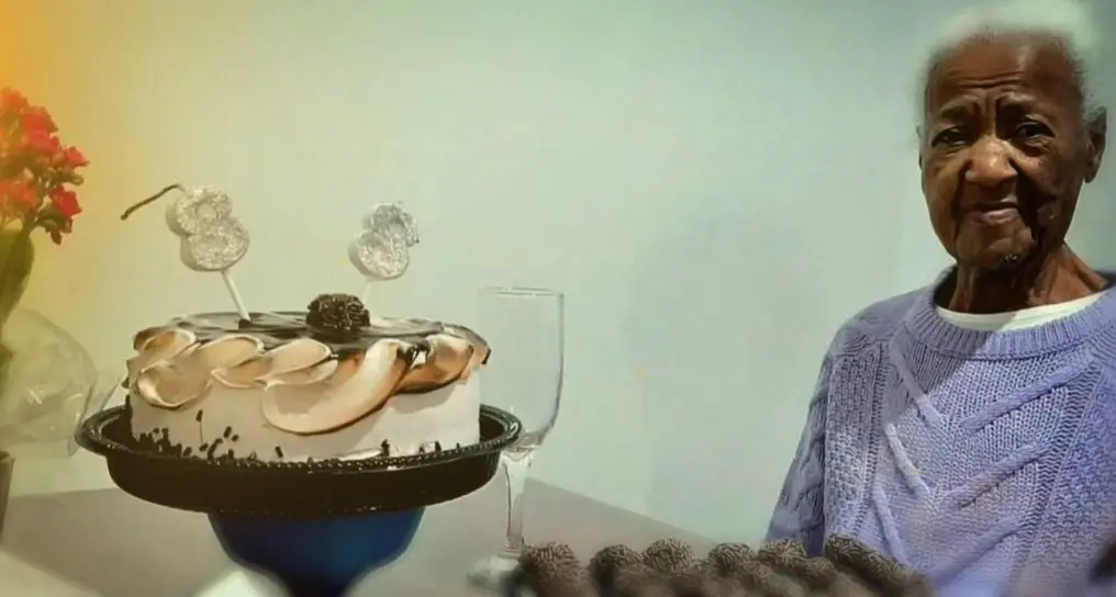 Idosa resgatada de situação de escravidão ao lado de bolo de aniversário