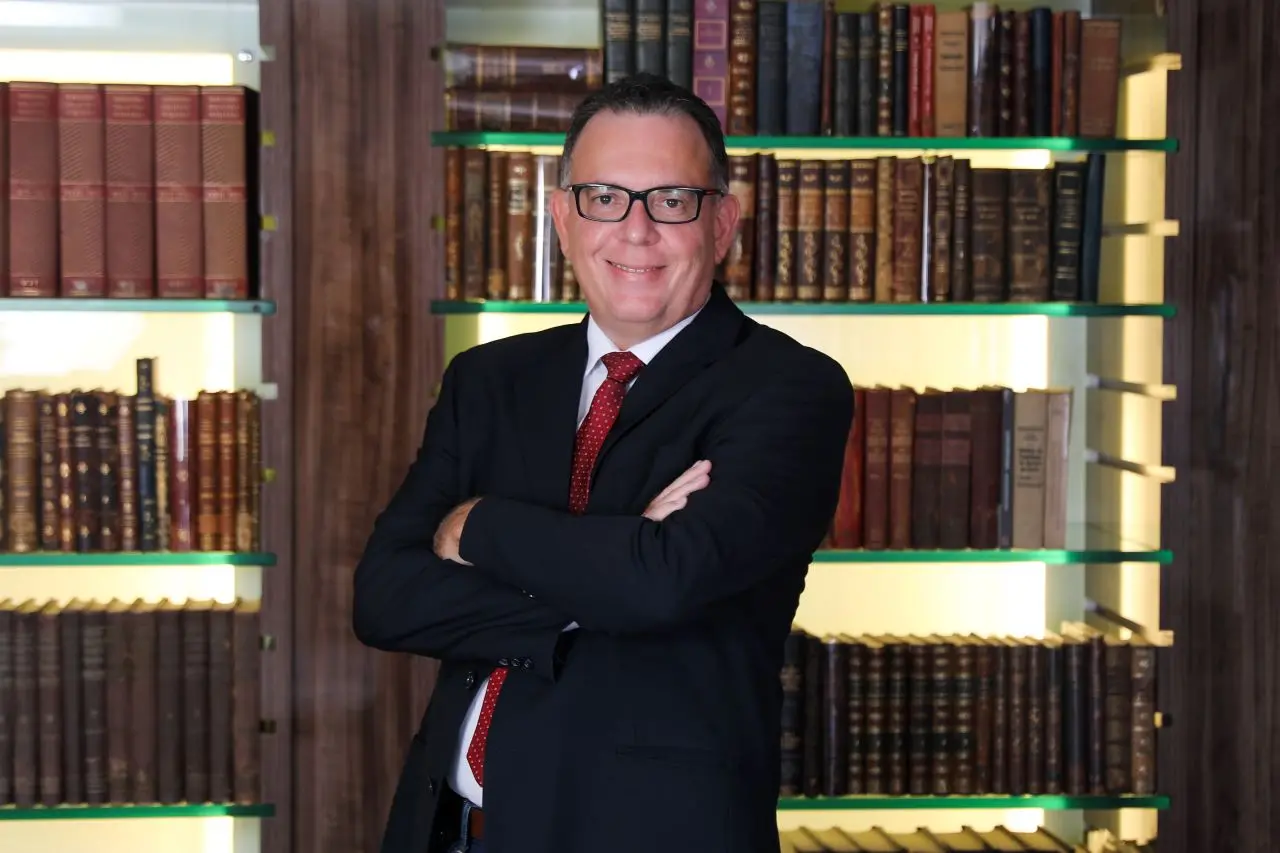 romulo leitão diante de estante de livros