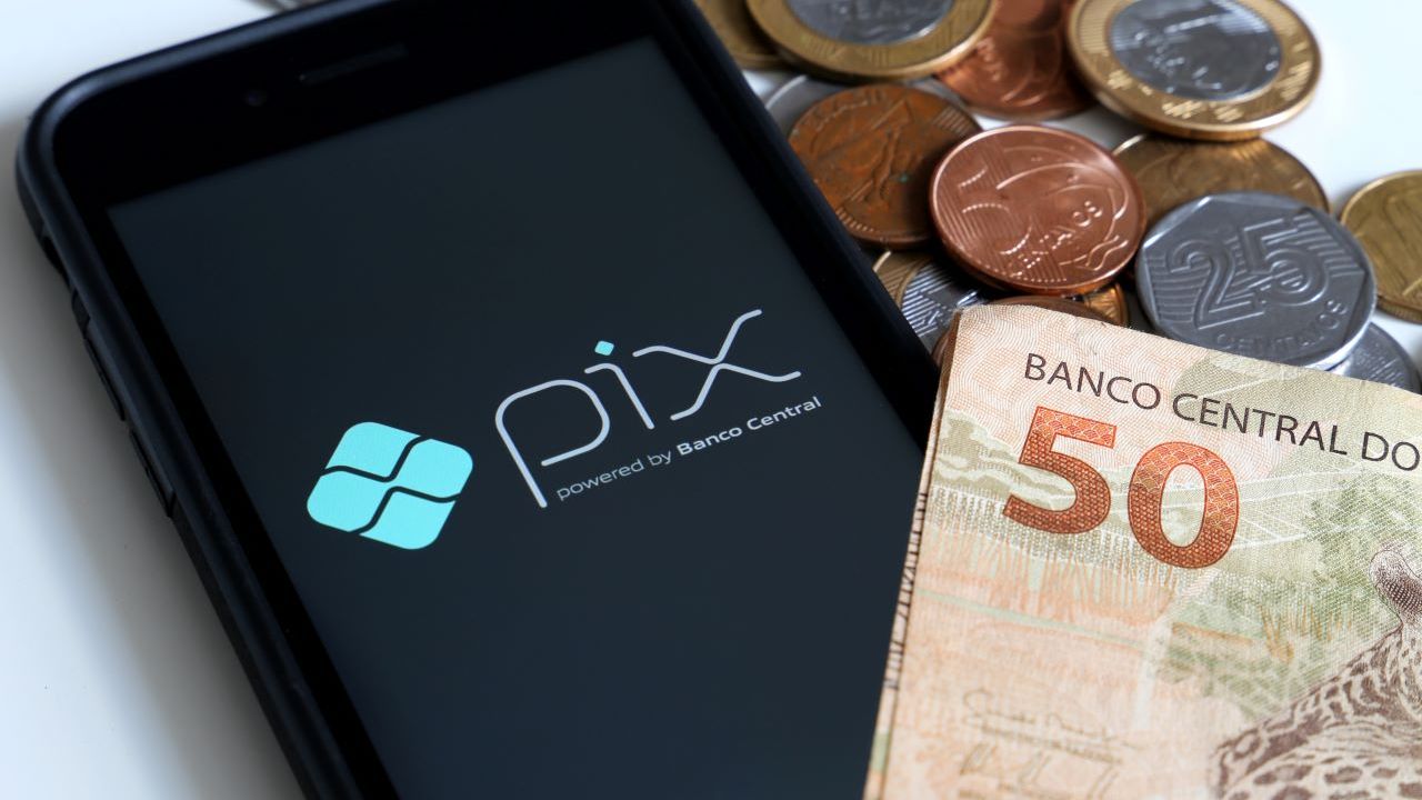 tela de celular com o nome pix ao lado de notas de dinheiro e moedas