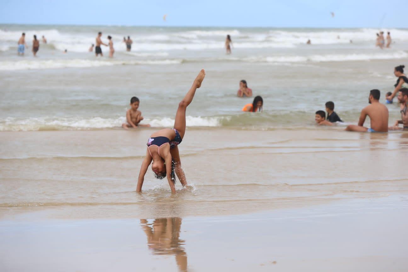 Criança faz acrobacia na praia