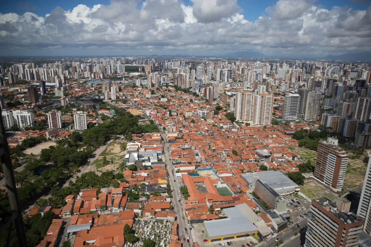 Imagem mostra vista aérea da cidade de Fortaleza, com prédio e telhados de casas.
