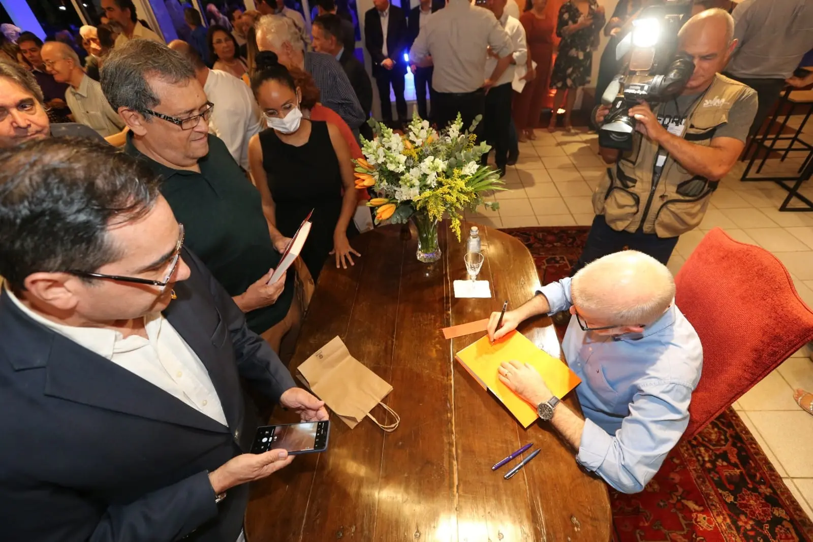 escritor lira neto autografando livro diante de platéia