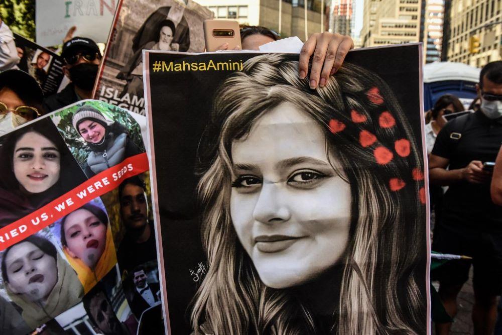 manifestante segura cartaz com a imagem da jovem Mahsa Amini durante protesto