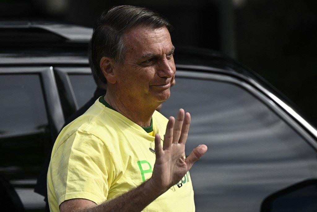 de camisa amarela, Jair Bolsonaro acenando