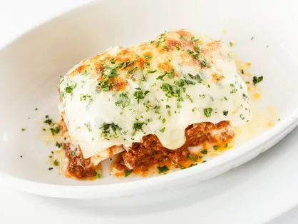 A lasanha pode ser servida com queijo parmesão ralado a gosto.