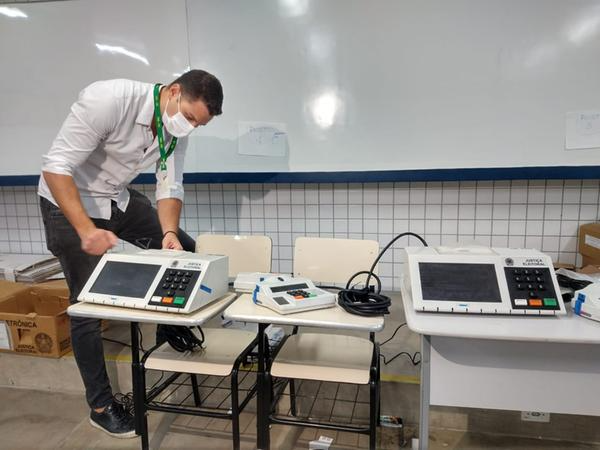 Homem manuseando uma urna eletrônica