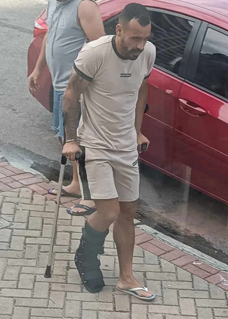 Moisés flagrado com bota ortopédica e muletas