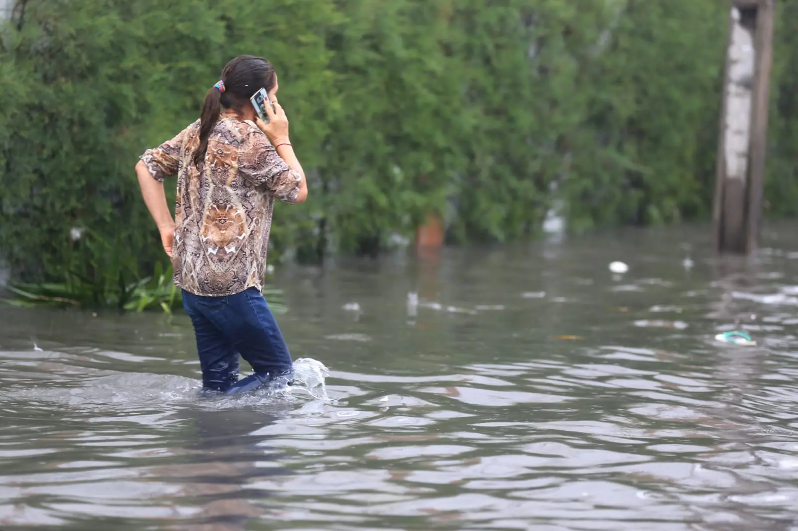 Mulher atravessa rua alagada