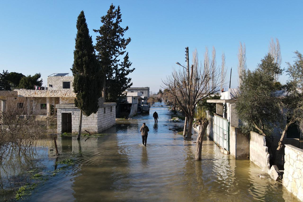 Uma vista aérea mostra pessoas caminhando por uma rua inundada na vila síria de Tloul, controlada pelos rebeldes, perto da fronteira com a Turquia, em 9 de fevereiro de 2023, depois que uma barragem desabou após um terremoto mortal que atingiu a Turquia e a Síria.