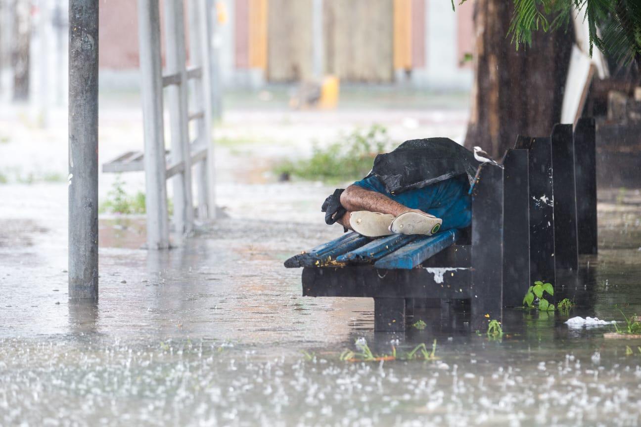 pessoa dormindo na parada de ônibus enquanto chove em Fortaleza