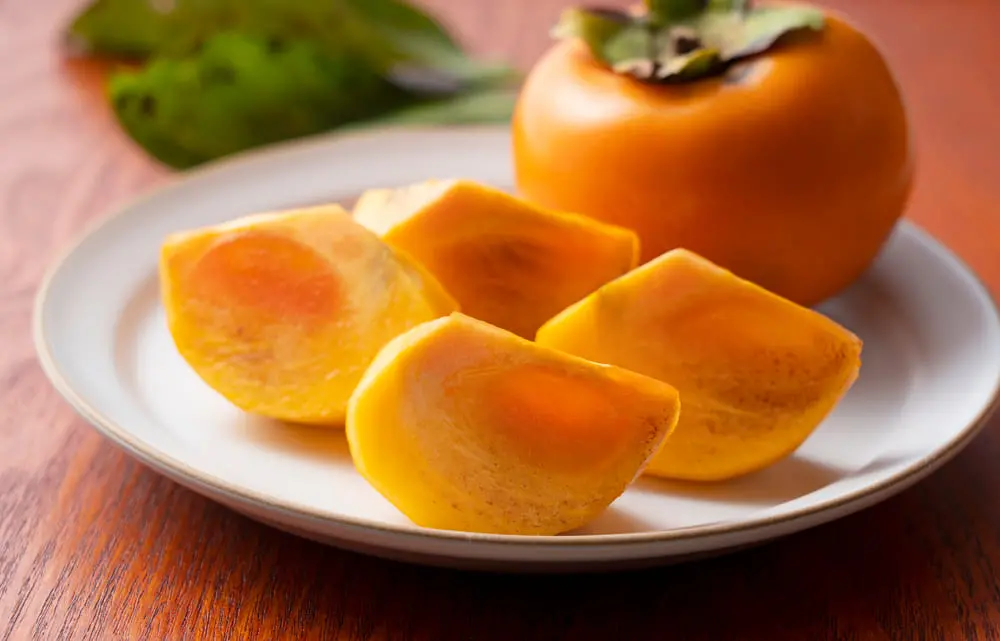 Pedaços de caqui sobre prato de porcelana