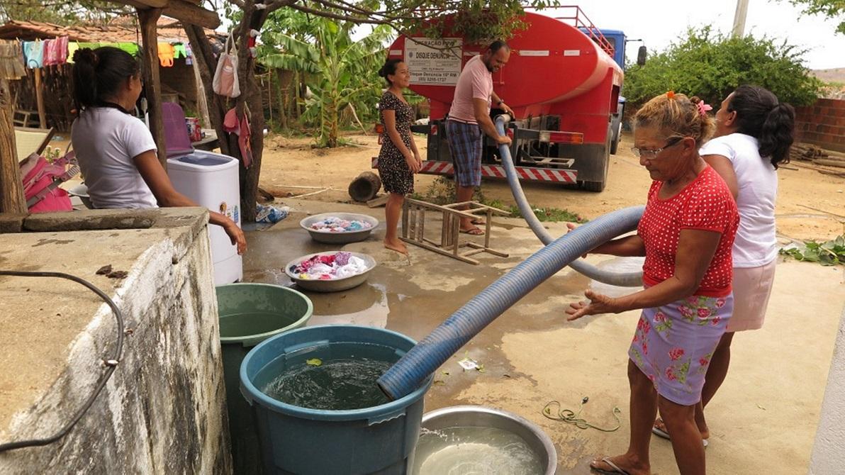 Mulheres e homem recolhendo água de carro-pipa no interior do Ceará