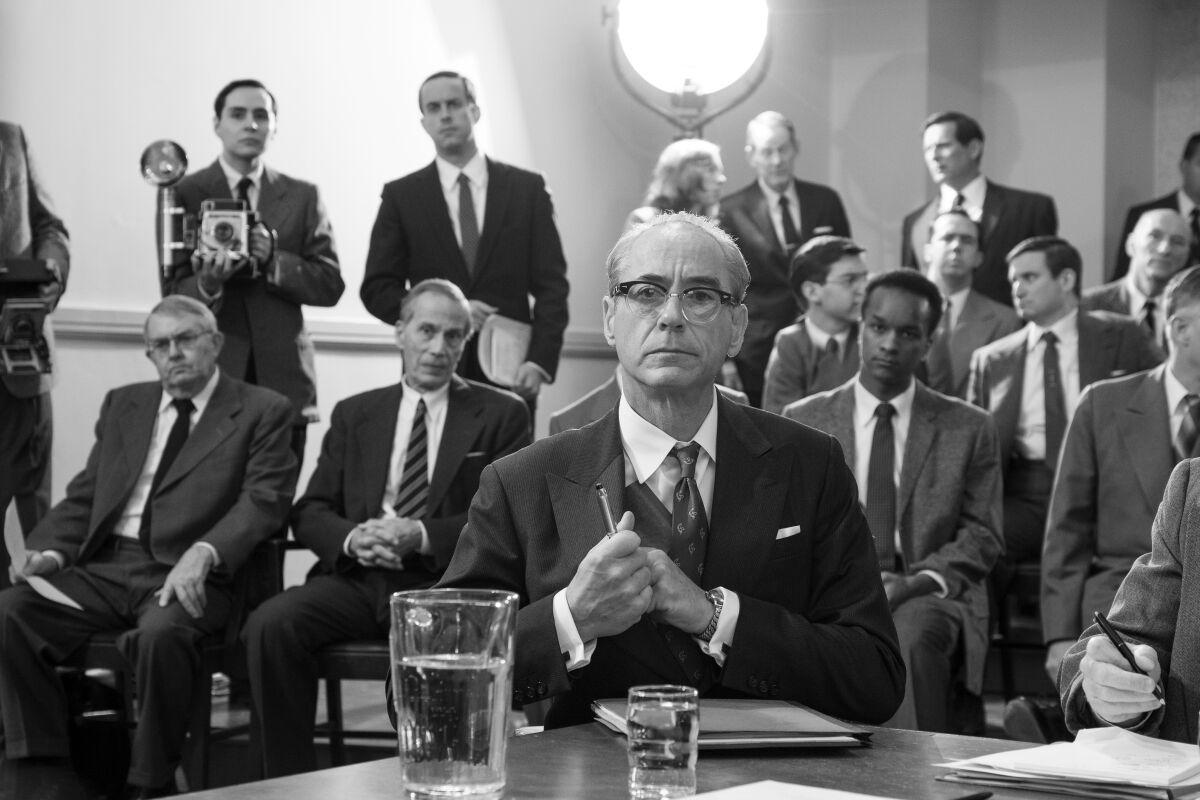 Reunião de homens de meia idade, usando ternos e gravatas, em uma espécie de tribunal
