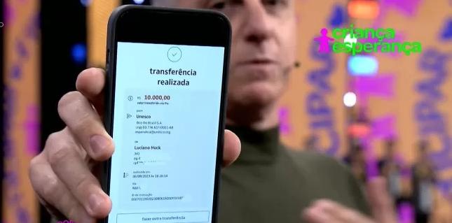 Luciano mostra tela do celular com comprante de doação de 10 mil reais ao Criança Esperança no dia 6 de agosto de 2023