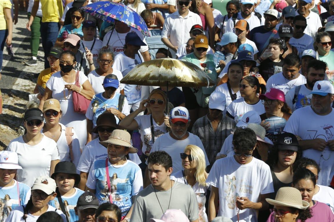 Com forte sol, Fieis utilizam óculos de sol e guarda-chuvas em Caminhada com Maria