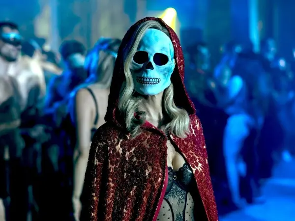 Mulher vestindo fantasia de caveira aparece parada em meio a uma festa