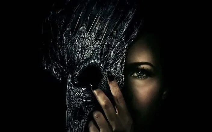 Mulher segura uma máscara de corvo diante do rosto