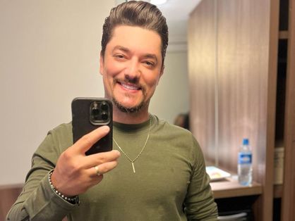 cantor  george henrique em foto no espelho sorrindo e blusa verde