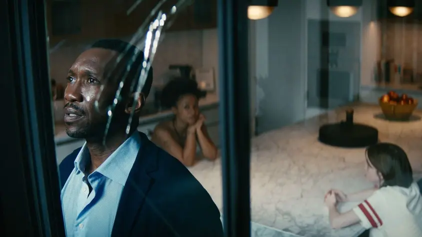 Homem de meia idade negro olha através de uma janela quebrada