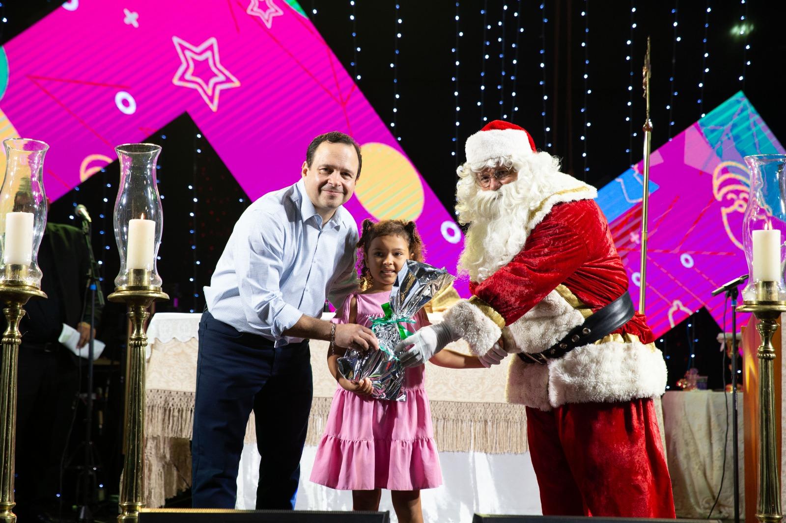 foto de Igor Queiroz Barroso ao lado de criança e papai noel no evento Natal Alegria a Praça