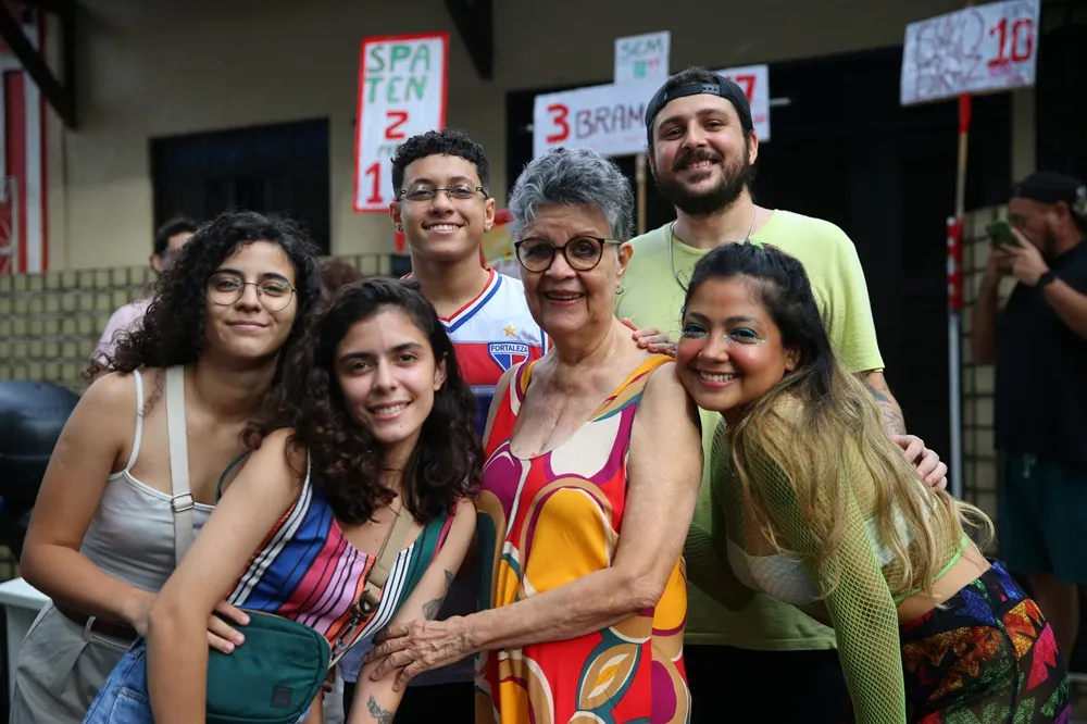 Gael, com a blusa do time do Fortaleza, se utiliza da casa da madrinha para vender bebidas com os amigos e se divertir