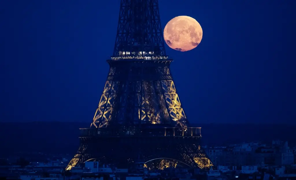 fotografia da Lua Cheia Rosa vista atrás da Torre Eiffel, em Paris