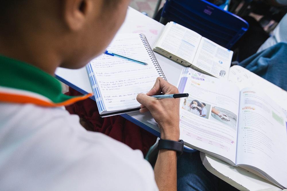 aluno de escola pública escrevendo em uma sala de aula