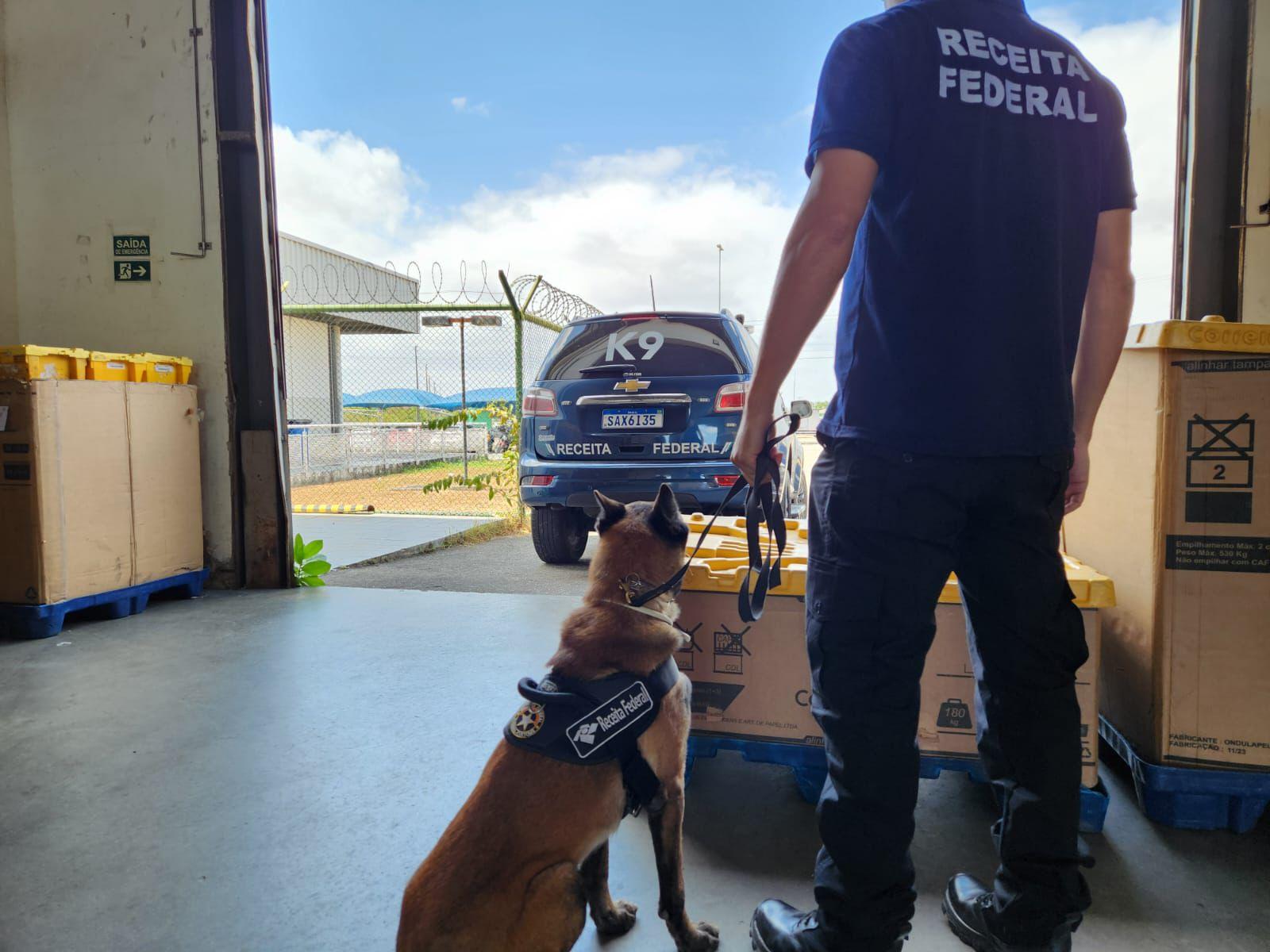 Agente da Receita Federal com cão farejador no terminal de cargas do Aeroporto de Fortaleza