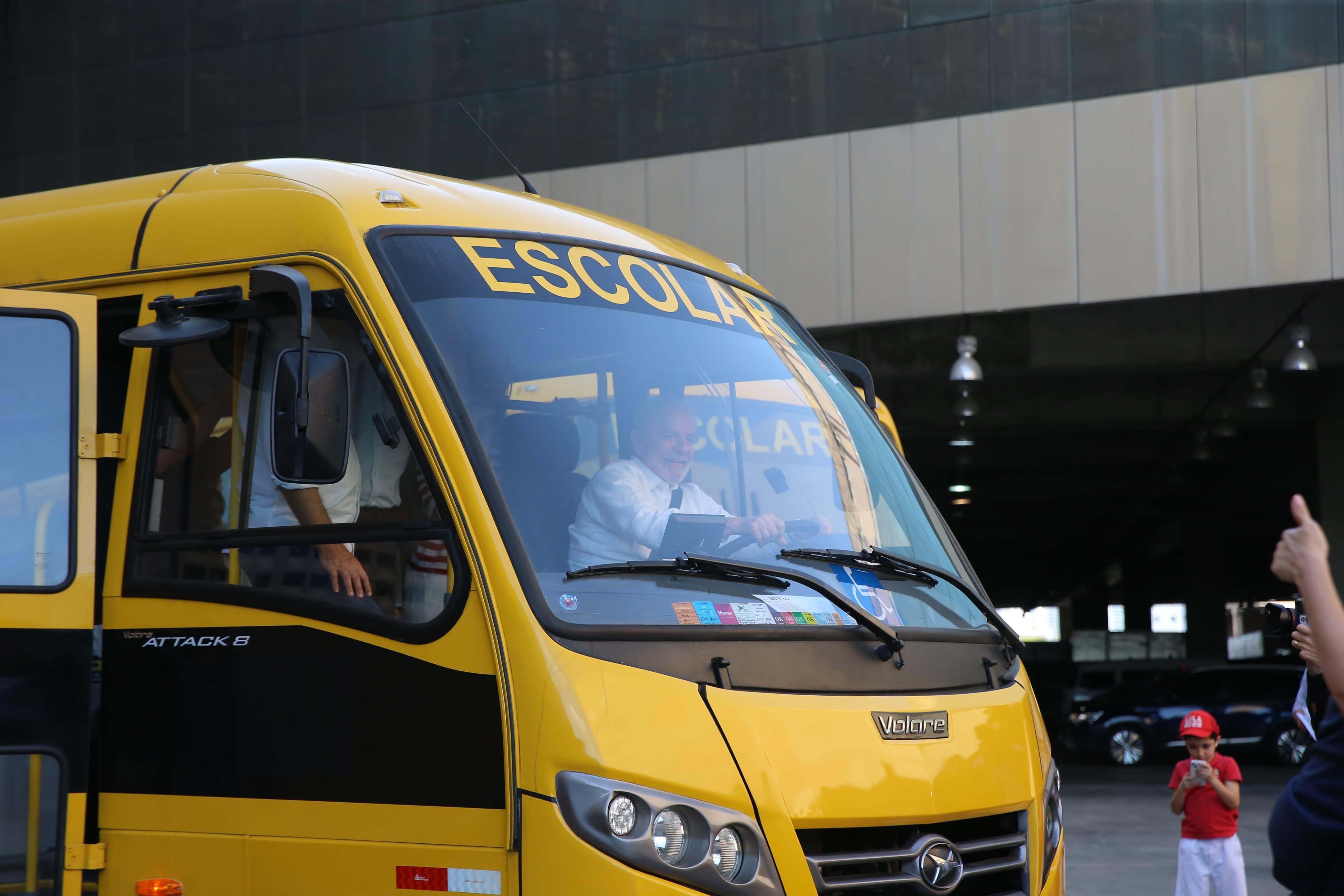 Presidente Lula simulando que está dirigindo um ônibus escolar