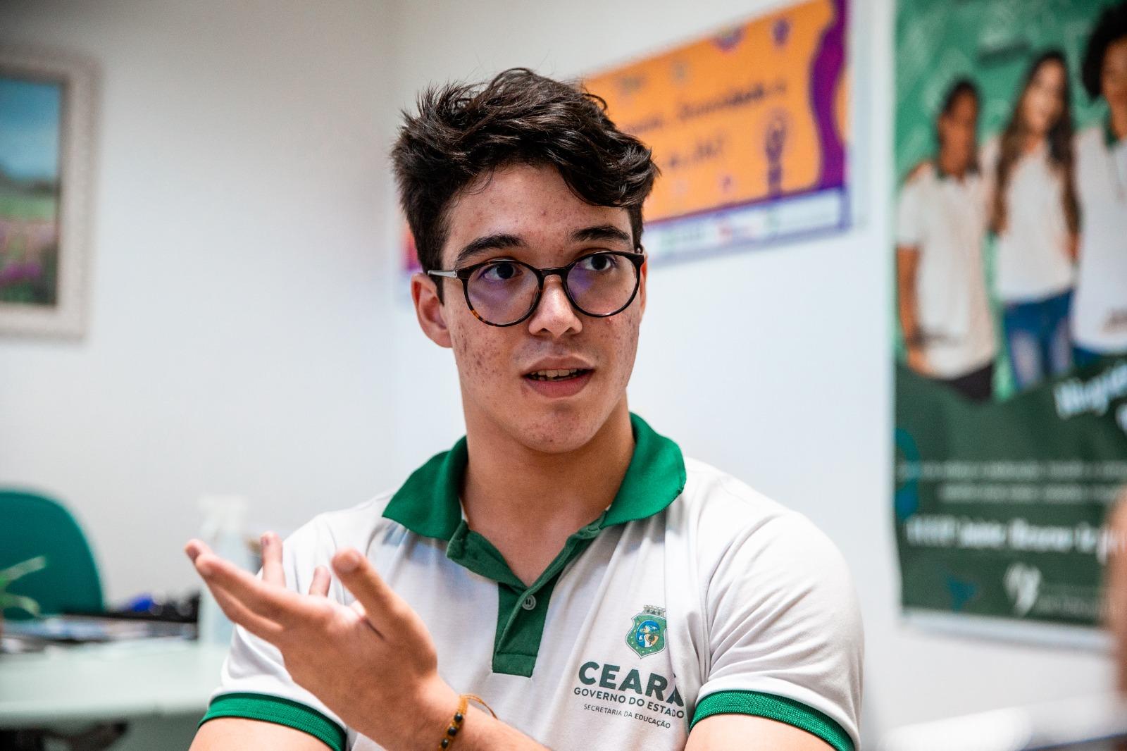 Jovem de óculos e cabelos escuros, vestindo a camisa da farda de uma escola pública do governo do estado do Ceará