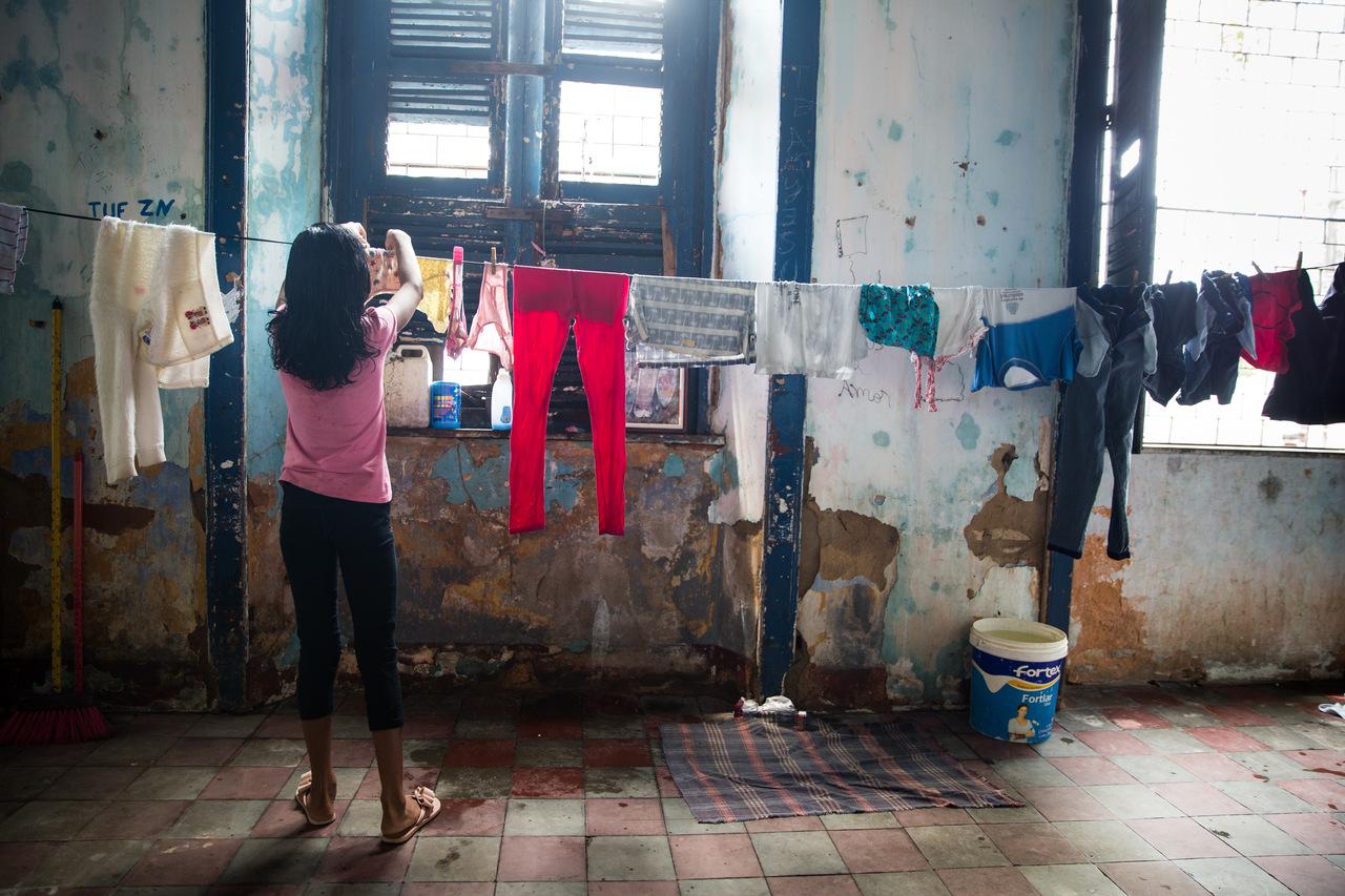 Menina realizando tarefa doméstica, pendurando roupa lavada em um varal