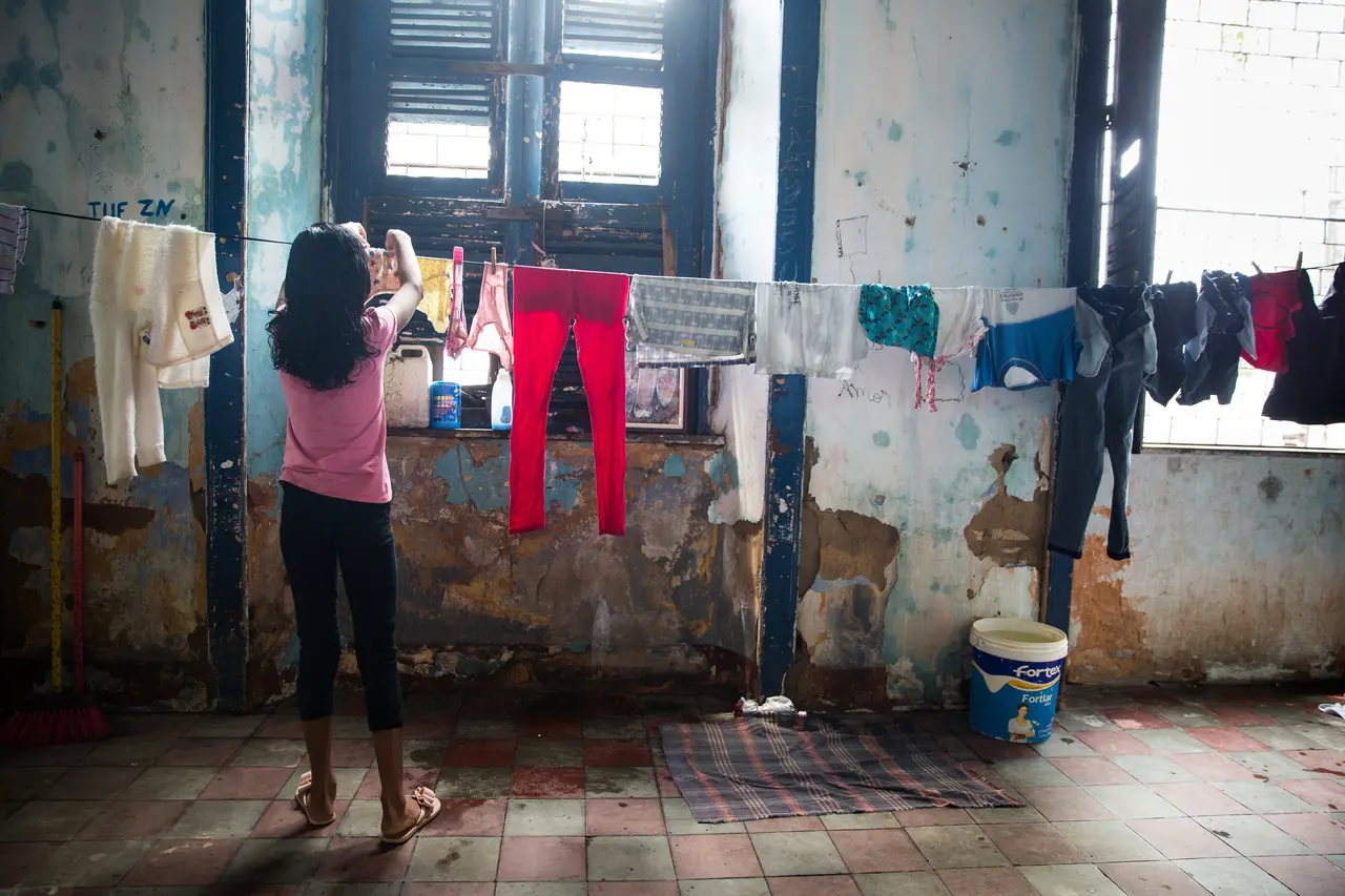 Menina realizando tarefa doméstica, pendurando roupa lavada em um varal