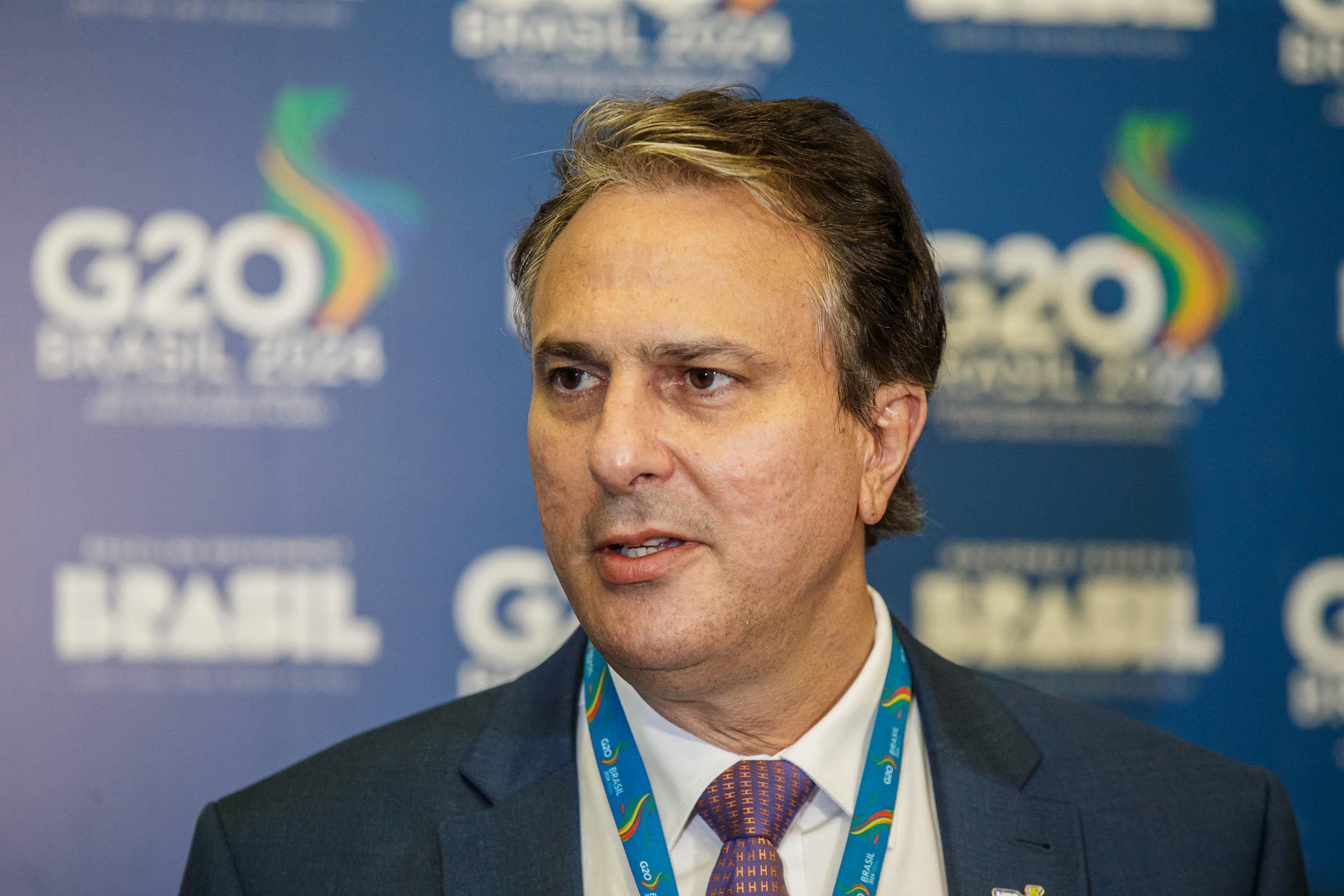 Ministro da Educação, Camilo Santana, em frente a um painel que exibe a marca do G20