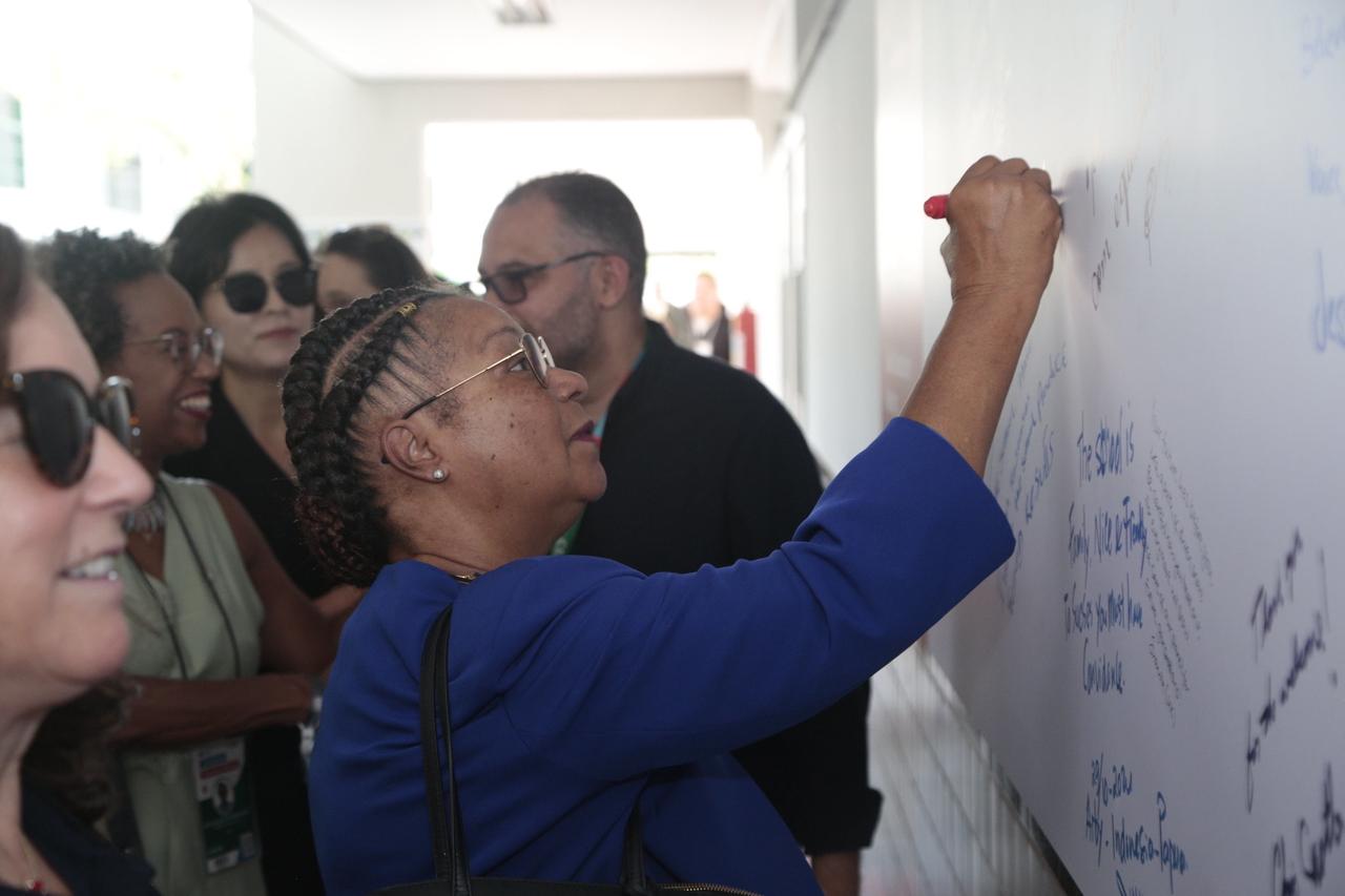 Mulher escreve mensagem em painel da escola