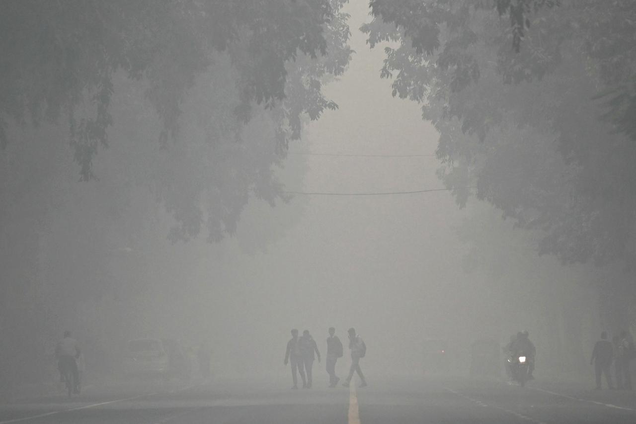 Pedestres atravessam uma rua em uma manhã fria e poluída em Nova Déli, em 18 de novembro de 2024.