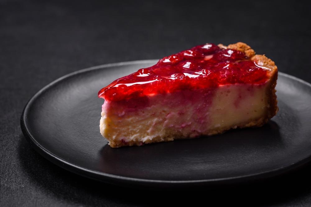 a imagem mostra uma fatia de cheesecake de frutas vermelhas, um dos doces de natal mais tradicionais, em um prato sobre a mesa