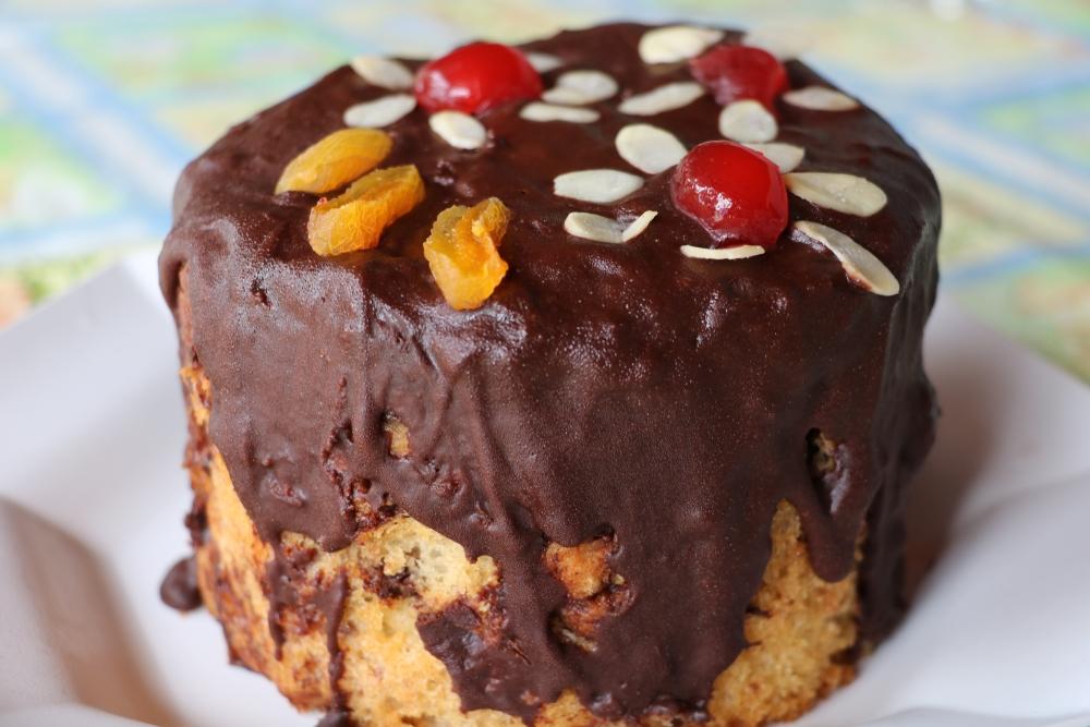 a imagem mostra um panetone com sorvete, cobertura de chocolate, frutas secas e sementes dentro de prato em cima da mesa