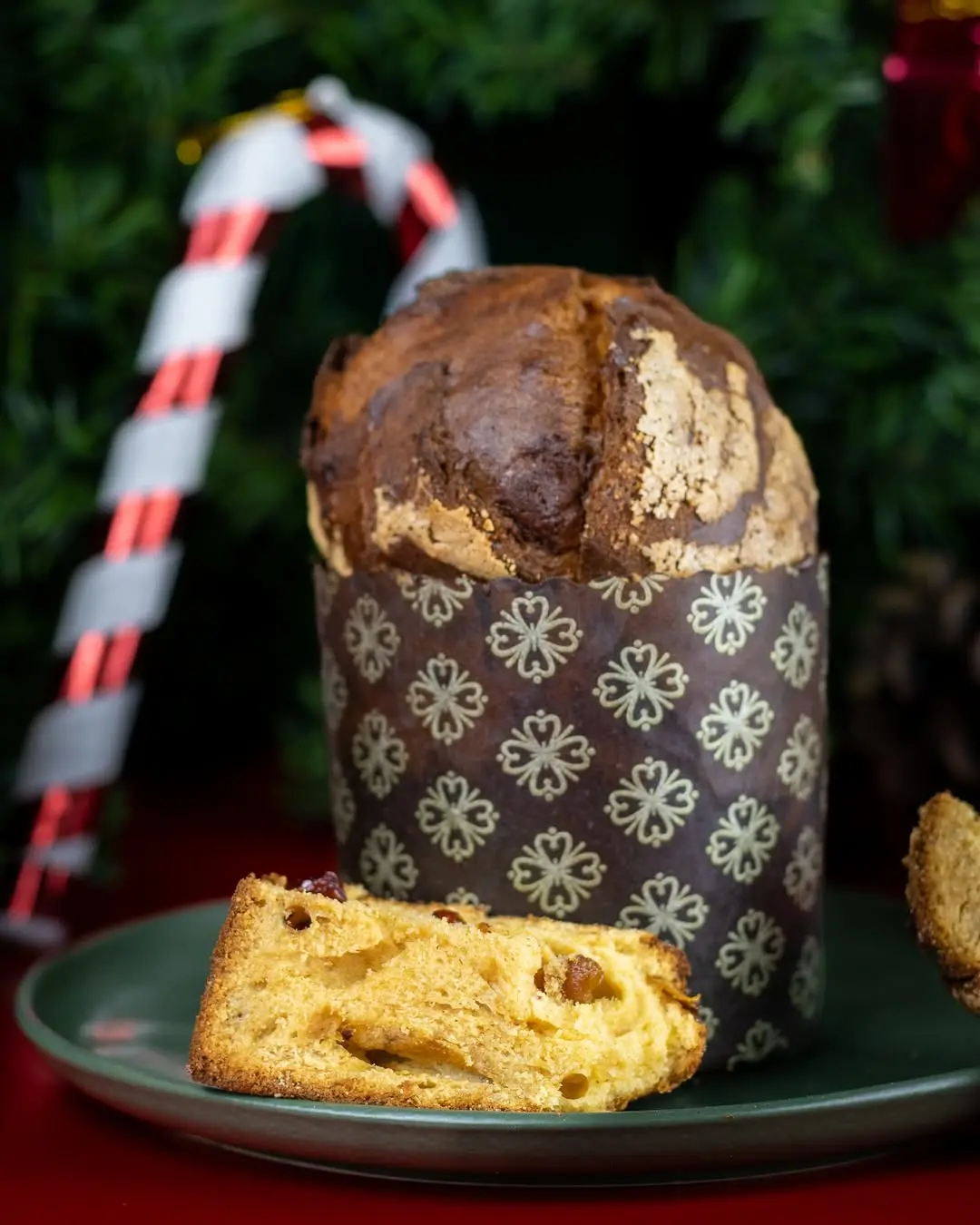 a imagem mostra um panetone de Ow Delícias em foco e uma árvore e bengala de natal ao fundo da foto