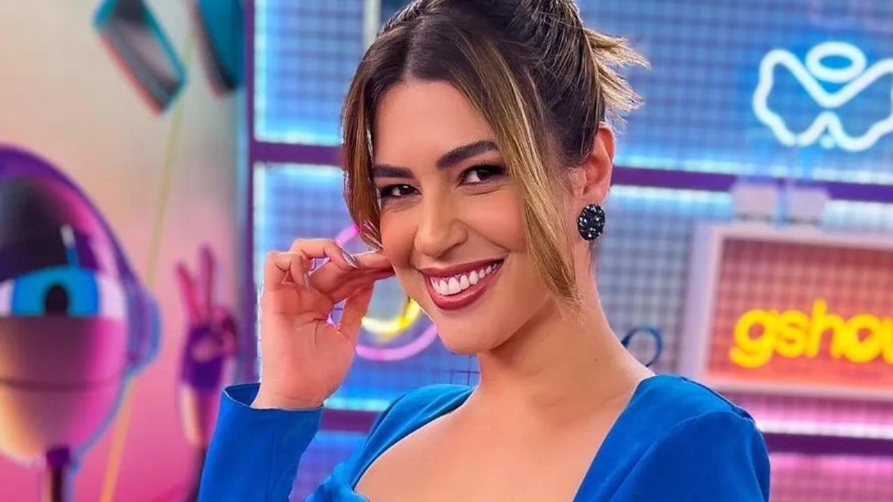 A imagem apresenta uma mulher sorridente vestindo um vestido azul, com um ambiente colorido e moderno ao fundo, ideal para captar a atenção do público.