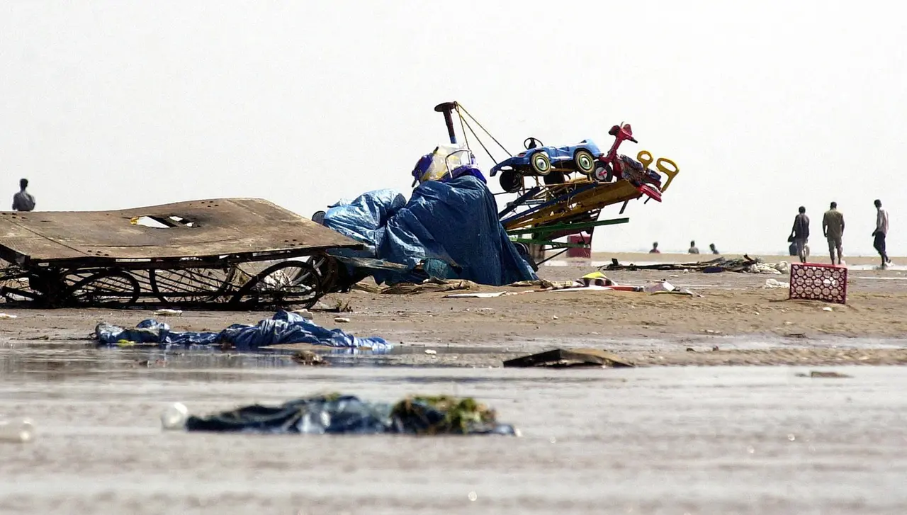 Indianos caminham entre destroços e veículos com rodas pequenas destruídos na praia de Marina, em Madras, em 26 de dezembro de 2004, depois que ondas gigantes atingiram a região. Ondas de 30 metros e mais de 220 mil mortos: tsunami considerado um dos piores da história completa 20 anos