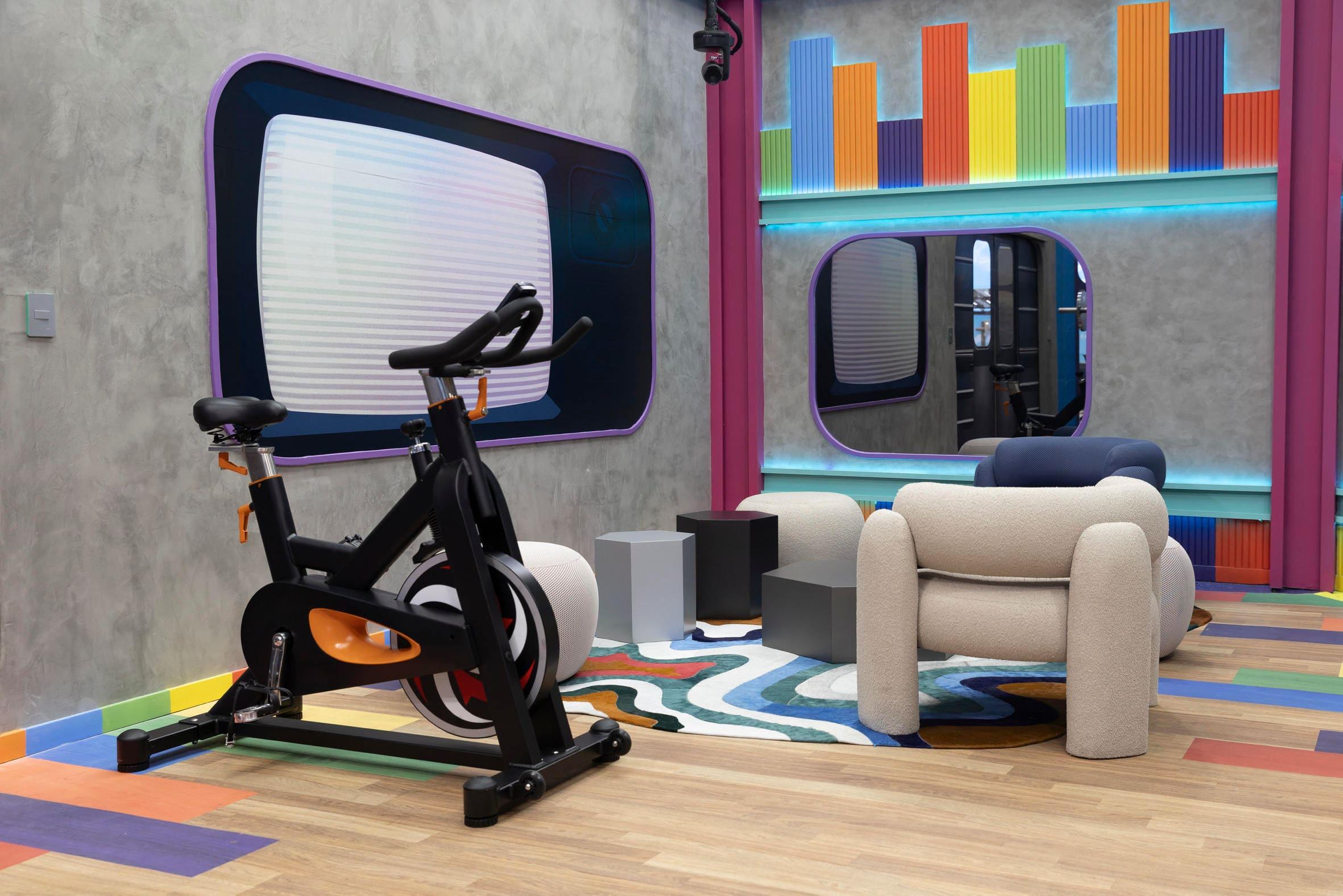 Um ambiente moderno e colorido com uma bicicleta de spinning, poltronas confortáveis e um tapete estiloso. Ideal para treinos e relaxamento