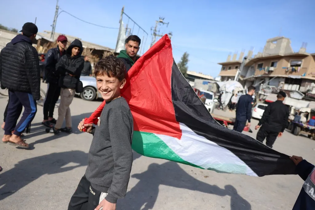 Criança carrega bandeira palestina em Nuseirat, centro da Faixa de Gaza, pouco antes da implementação do cessar-fogo