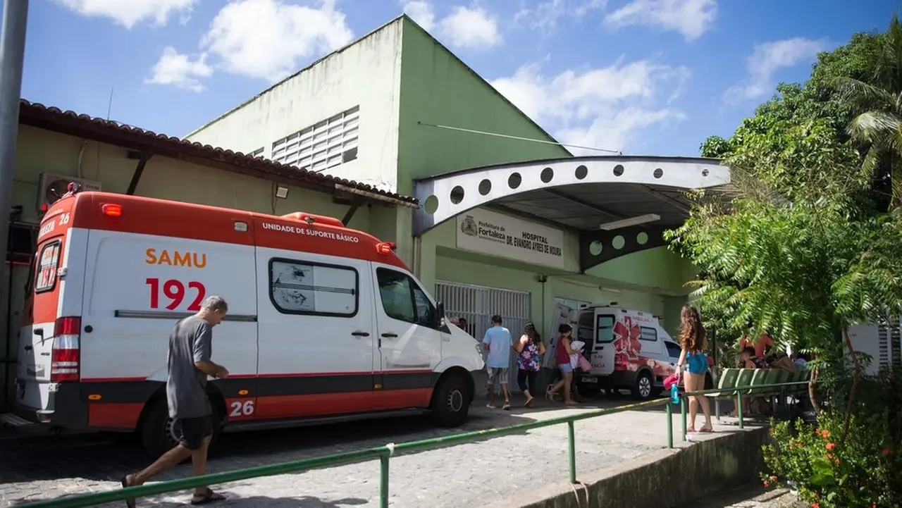 Fachada do Hospital Distrital Evandro Ayres de Moura (Frotinha Antônio Bezerra), em Fortaleza, com uma ambulância do Samu na frente e pacientes aguardando do lado de fora e entrando na unidade