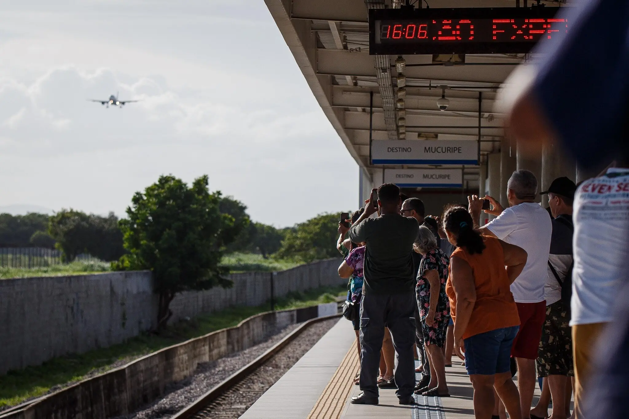 Pessoas na plataforma do Metrô de Fortaleza, observando a chegada do avião