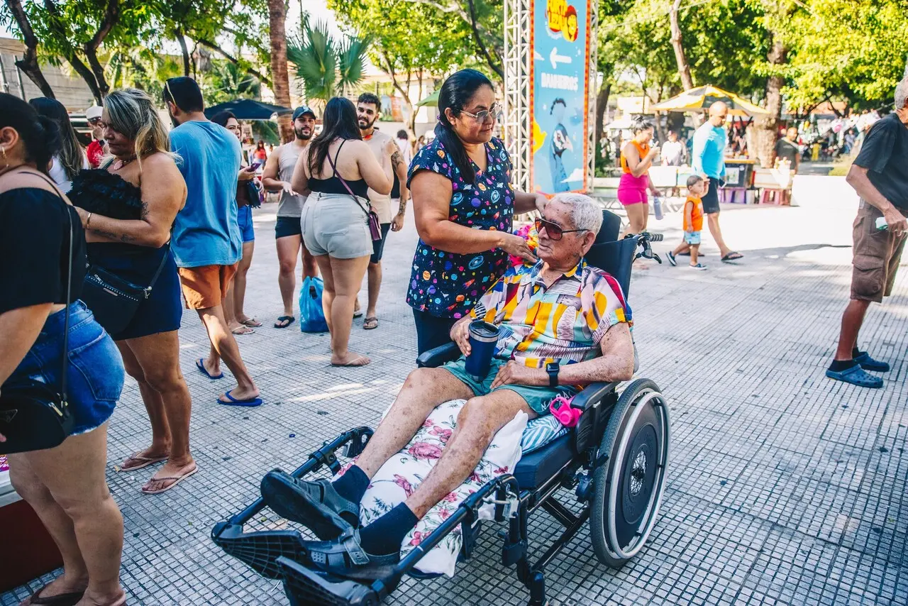 Foto de idoso ao lado de cuidadora no pré-carnaval de fortaleza