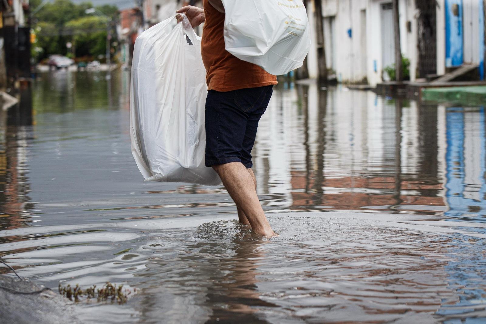 Morador cruza rua alagada no bairro Aerolândia