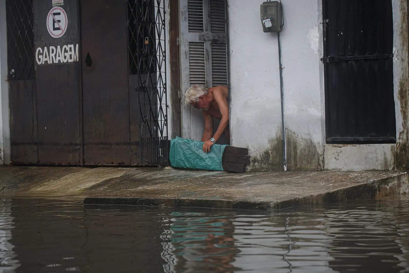 Homem coloca tábua para barrar água