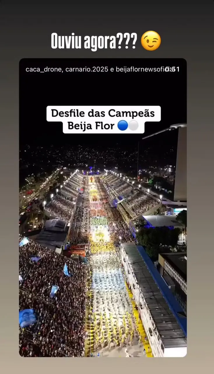 Vista aérea do desfile das campeãs da Beija Flor, com uma grande multidão e uma apresentação vibrante durante a celebração de carnaval.