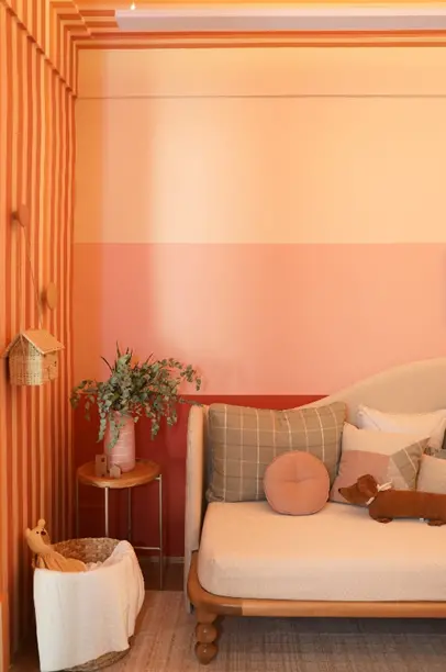 Um degradê de cores em tons de tosa com faixas delimitando cada uma na parede do quarto de uma bebê. A transição sutil entre as cores proporciona um ambiente leve e envolvente