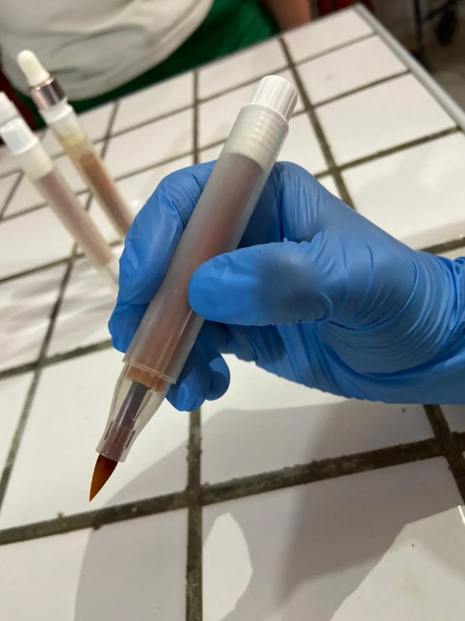 Mão com uma luva segurando a caneta criada pelas estudantes